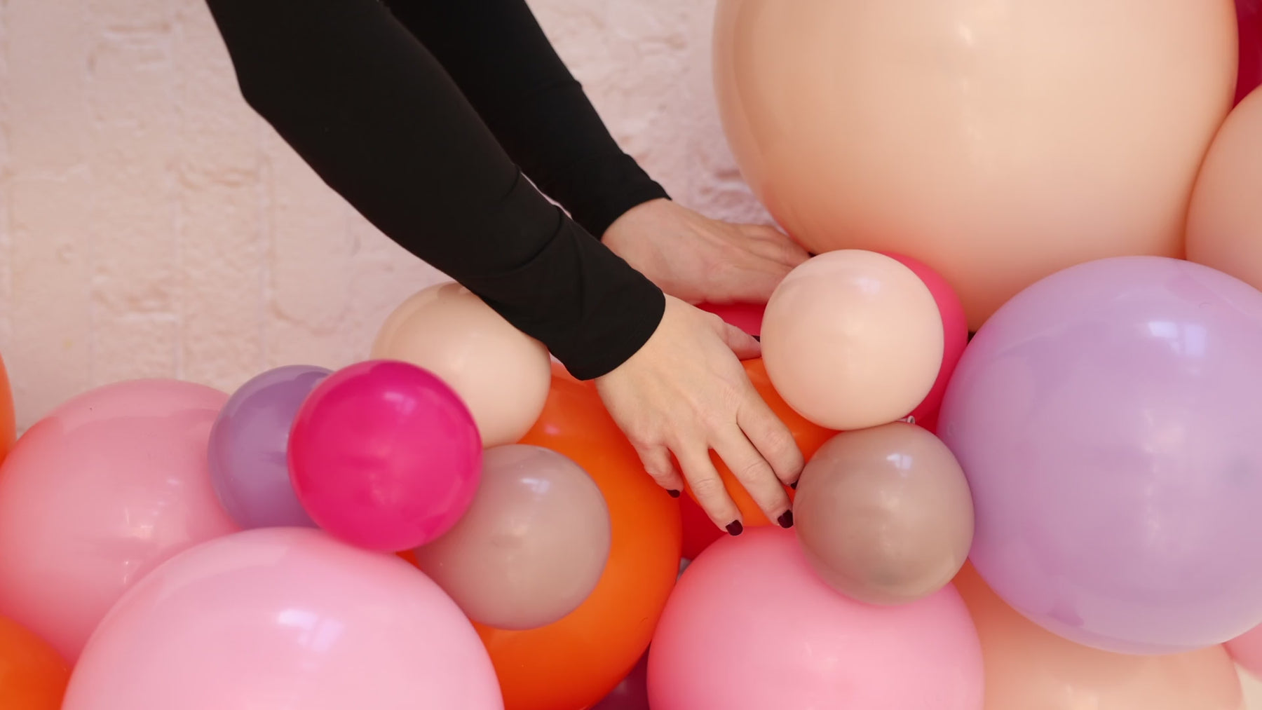 Founder of 99 Haus Balloons and Decor constructing and testing a colorful balloon column