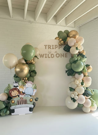 A safari themed party backdrop with balloons and leaves