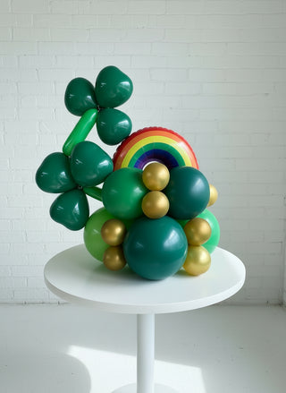 A balloon display featuring a rainbow and clover design, predominantly in green and gold colors, intended for St. Patrick's Day celebrations.