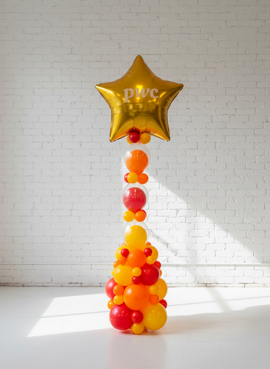 A decorative balloon column with a star topper, featuring a staircase of orange and yellow balloons leading up to a gold star-shaped balloon.