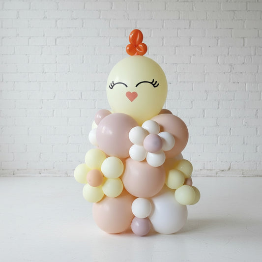 A decorative balloon column designed to look like an Easter chick with pastel colors and a smiling face.