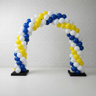 A classic balloon arch with a gradient of blue, white, and yellow balloons, set against a indoor background